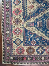 a large antique sumac rug with pink and royal blue accents on a taupe field