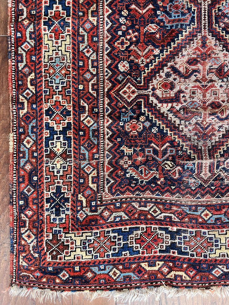 an antique shiraz qashqai rug with a navy blue field and red accents