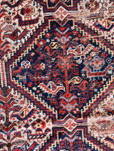 an antique shiraz qashqai rug with a navy blue field and red accents