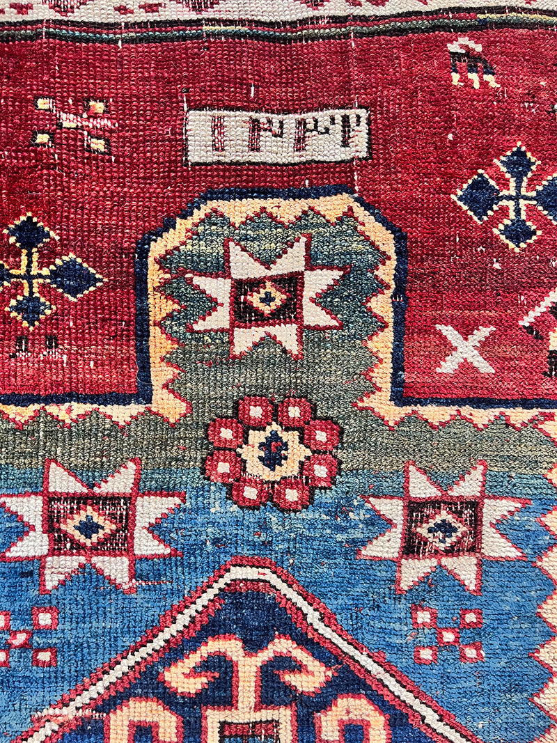 a mini antique kazak rug with a prussian blue field and red and yellow accents