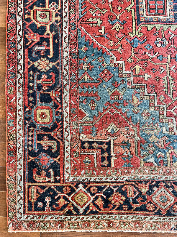 a large antique Heriz rug with a red field and dark blue medallion and border