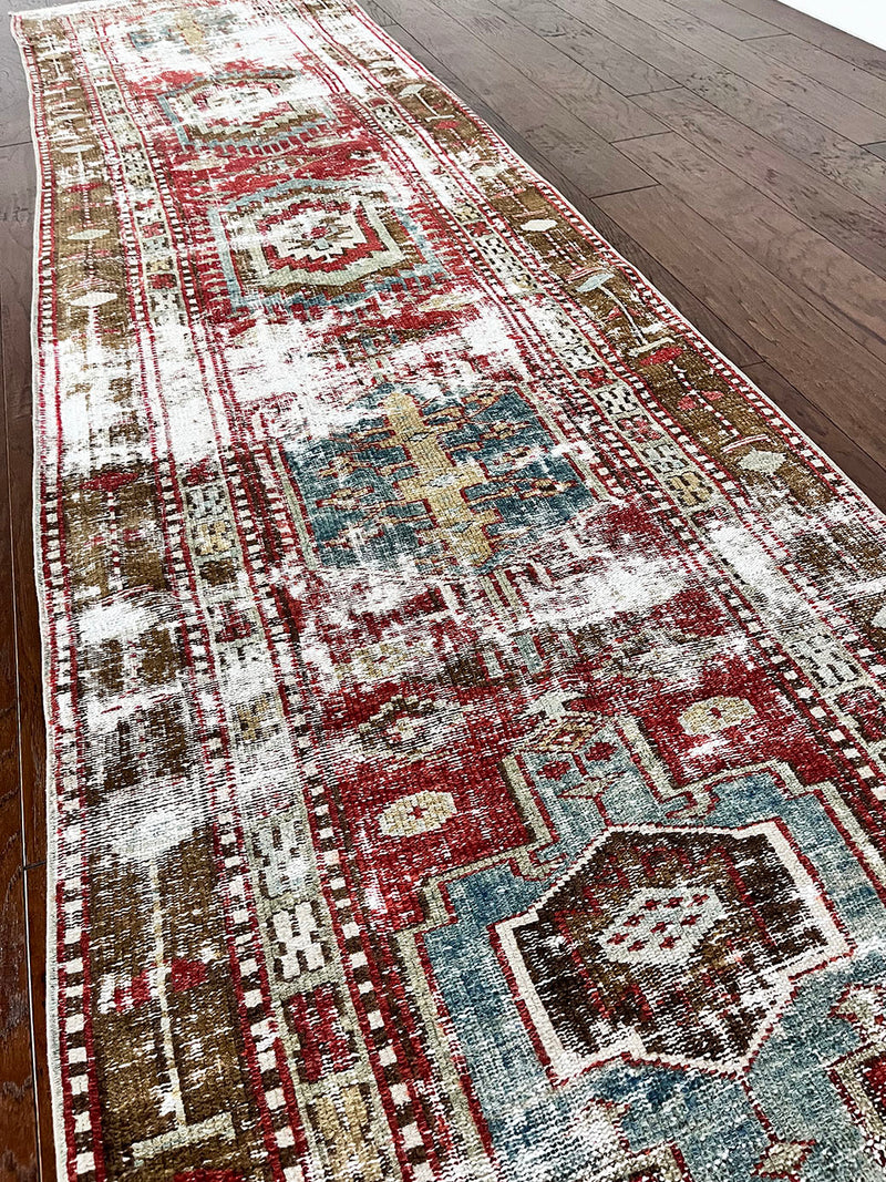an antique heriz runner with a faded red, blue and brown palette and substantial patina