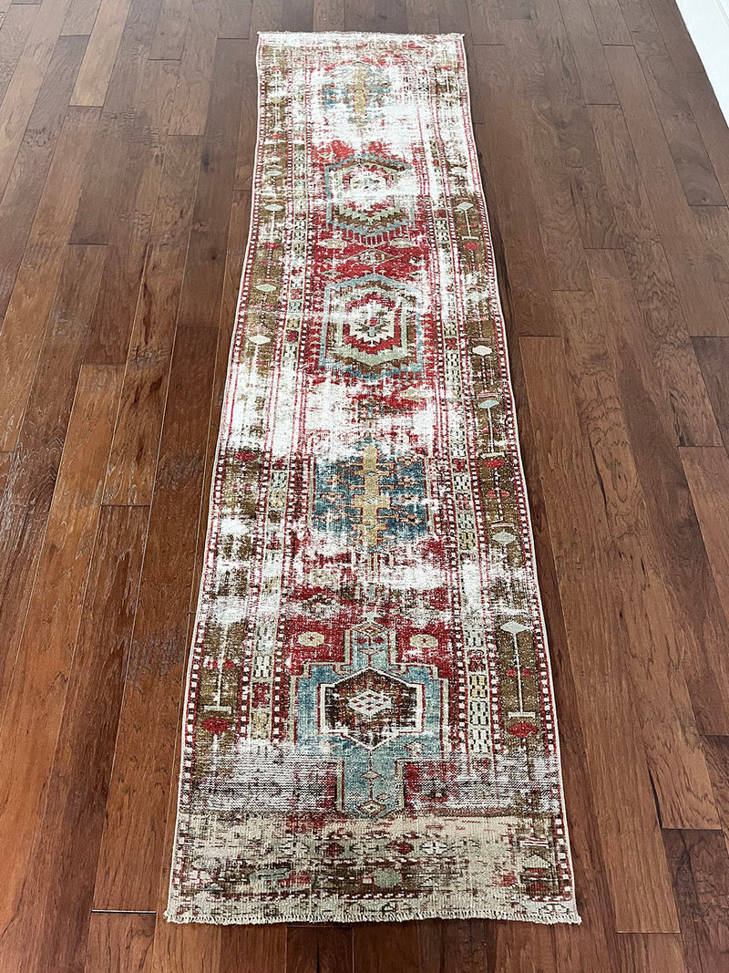 an antique heriz runner with a faded red, blue and brown palette and substantial patina