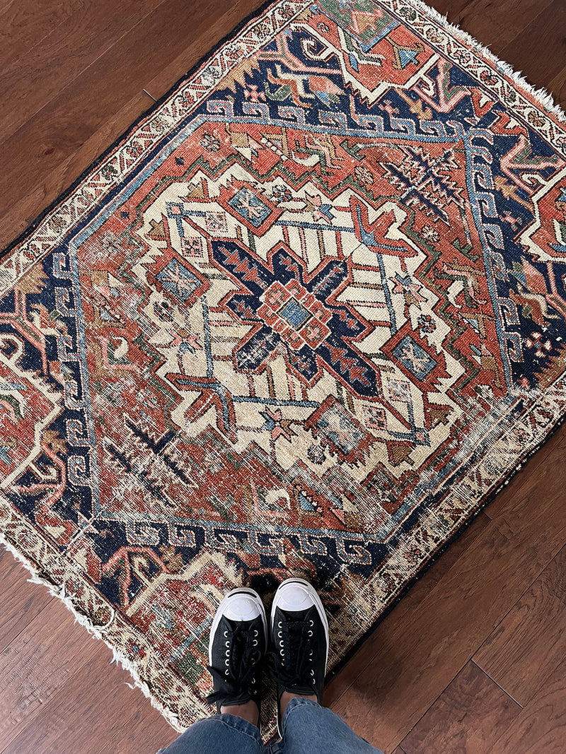a mini antique heriz rug with a pretty rust field and dark blue, green and salmon pink accents