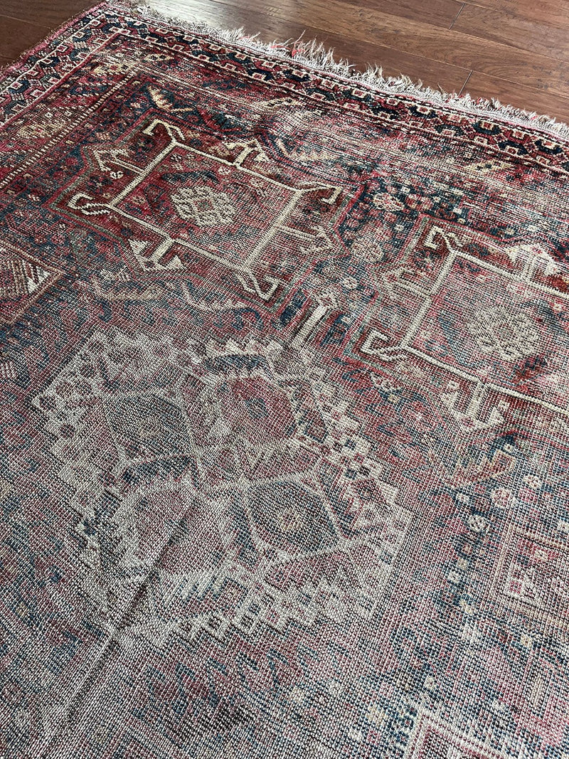 a large shiraz rug with a faded brown palette and soft red accents