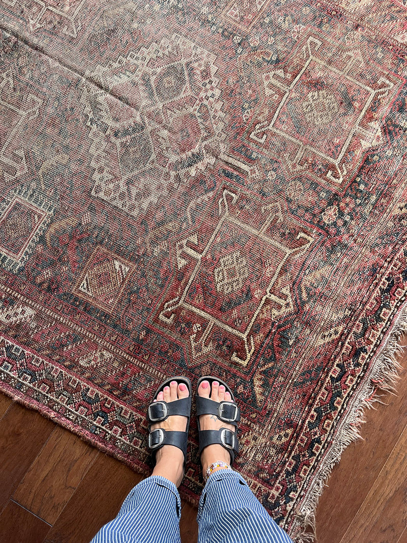 a large shiraz rug with a faded brown palette and soft red accents