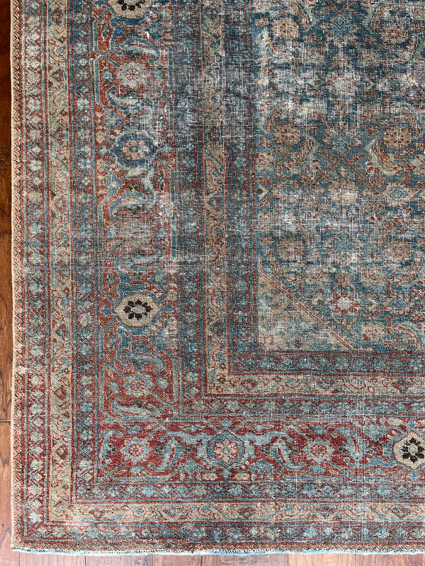 an antique tabriz rug with a teal field, red border and a delicate floral pattern