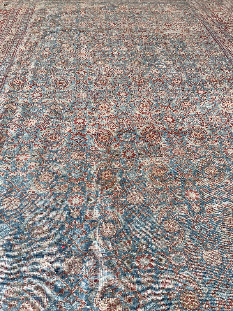 an antique tabriz rug with a teal field, red border and a delicate floral pattern