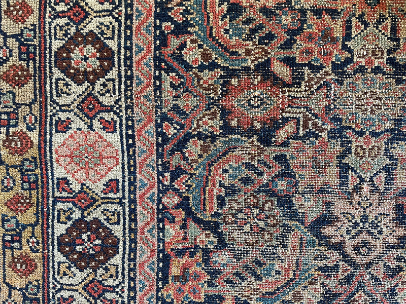 an antique malayer rug with a classic dark blue field and coral pink floral trellis design 