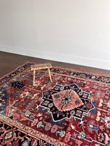 a large antique heriz rug with a red field and midnight blue medallion