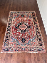 a large antique heriz rug with a red field and midnight blue medallion