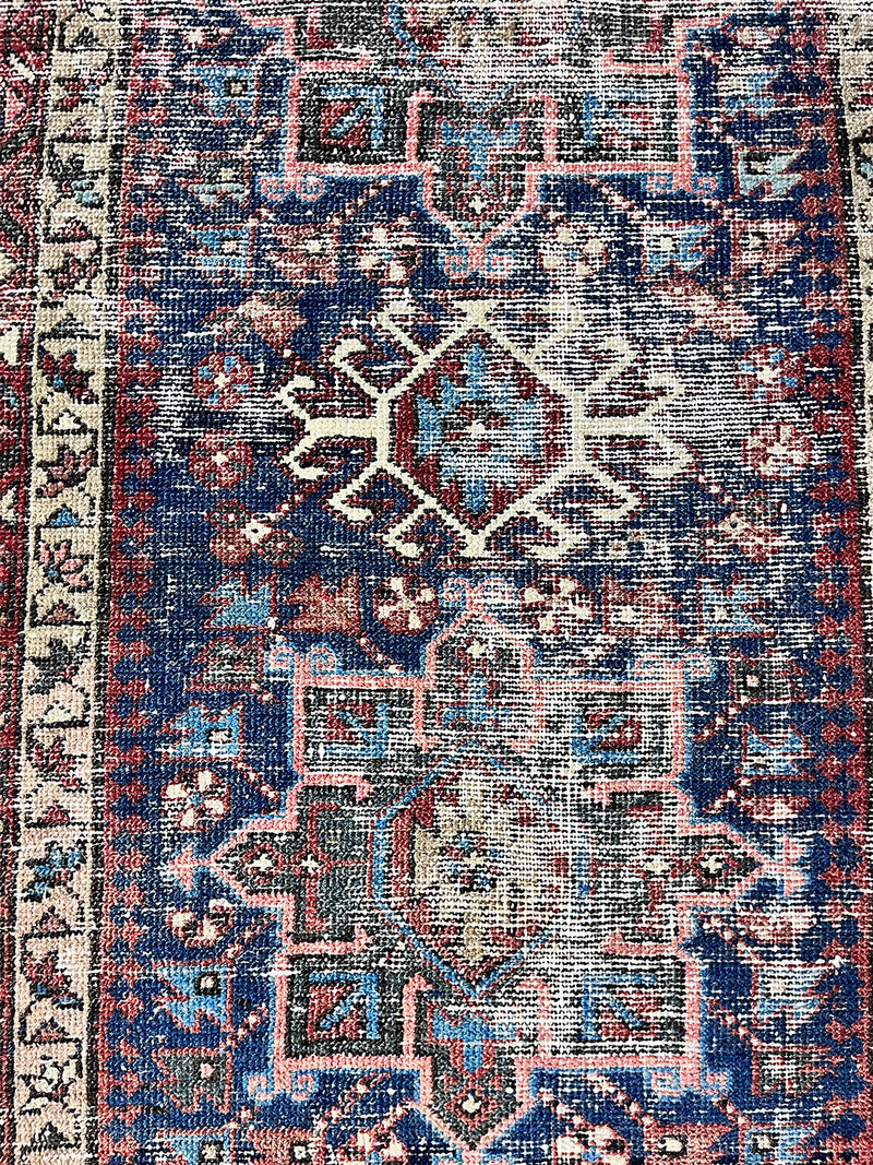 a mini antique heriz karajah rug with a dark blue field and green, pink and rust accents