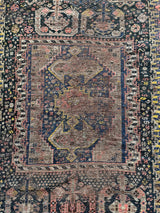 an antique shiraz rug with midnight field and yellow and pink accents