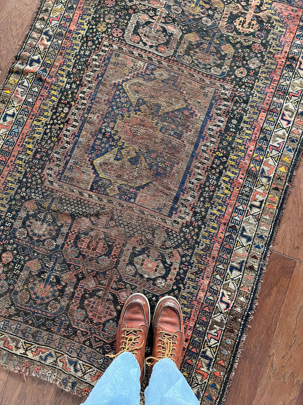 an antique shiraz rug with midnight field and yellow and pink accents