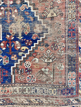 an antique qashqai rug with a dark blue field and rusty red/brown accents 