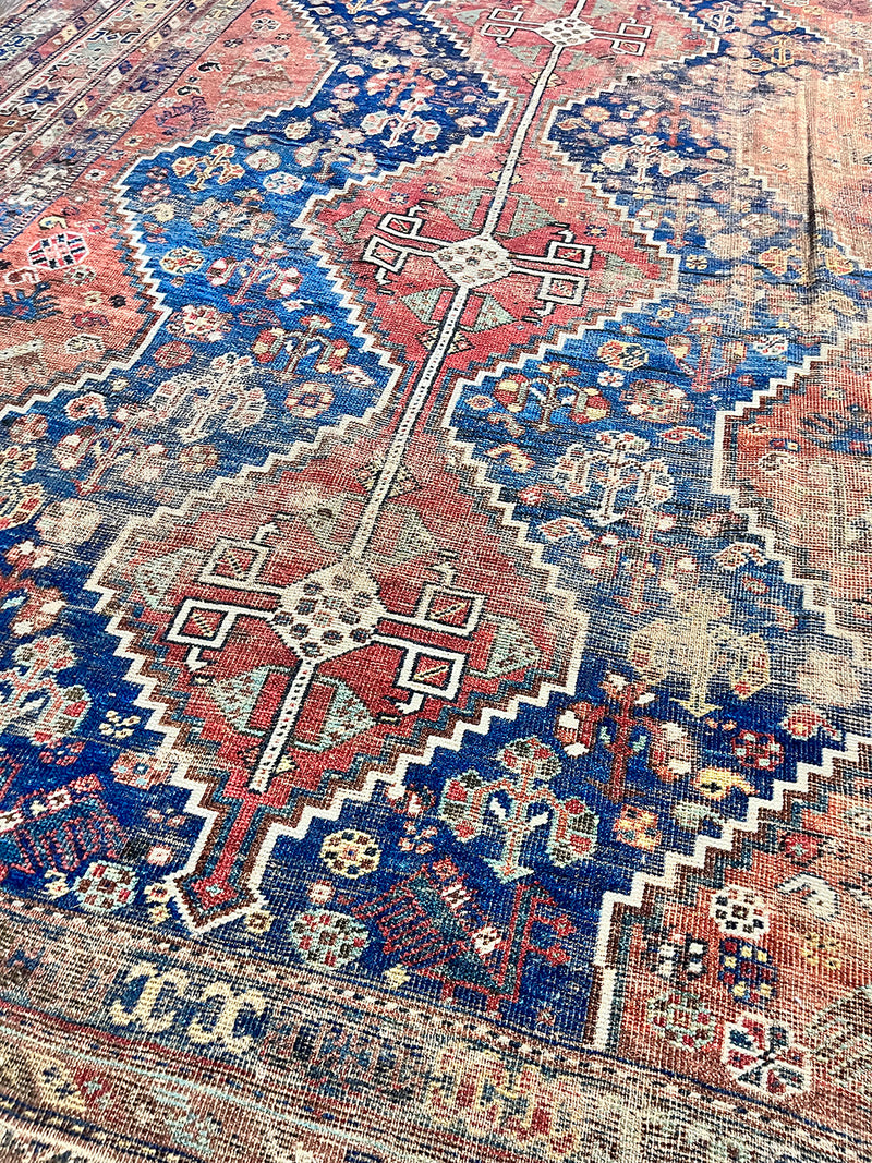 an antique qashqai rug with a dark blue field and rusty red/brown accents 