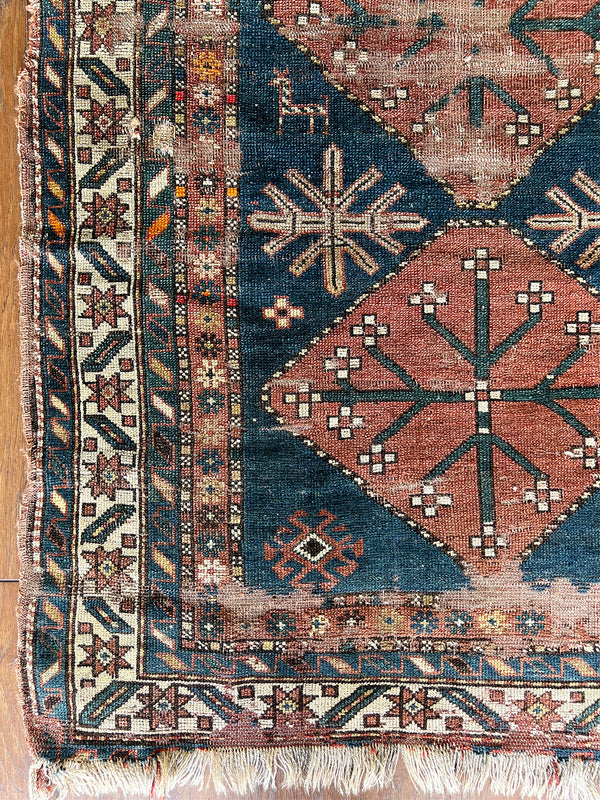 an antique caucasian rug with a dark prussian blue field and three coral-toned medallions