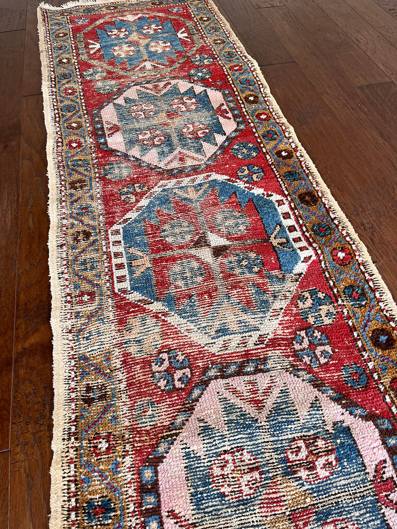 an antique heriz runner with a red field and royal blue medallions