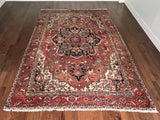 a large antique serapi rug with a coral field and large dark blue medallion