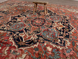 a large antique serapi rug with a coral field and large dark blue medallion