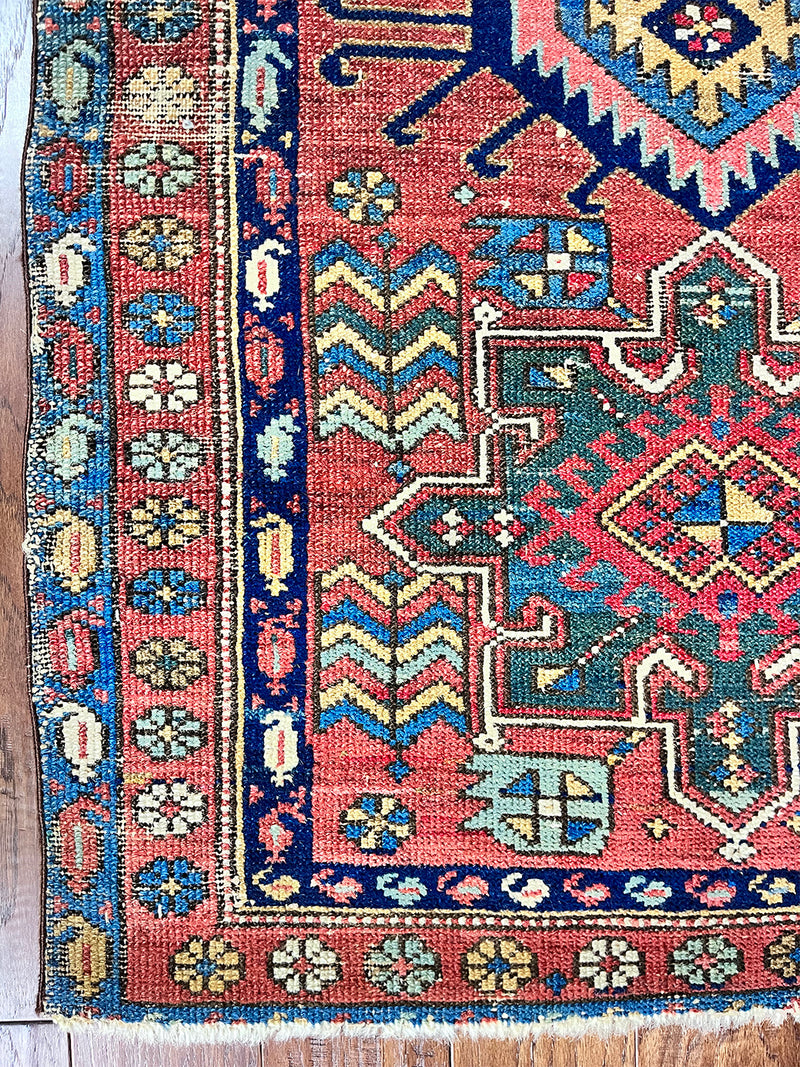 a mini antique heriz karajah rug with a coral field and blue, yellow and green accents
