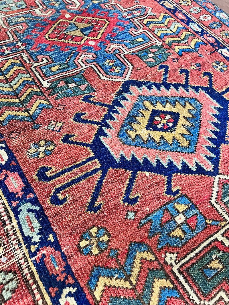 a mini antique heriz karajah rug with a coral field and blue, yellow and green accents
