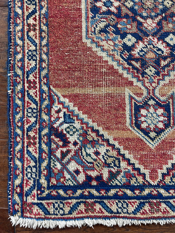 a mini tabriz rug with a coral field and a navy blue medallion and border