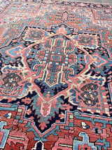a large antique heriz rug with a coral field and bright icy blue, pink and coral accents