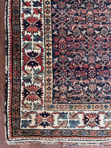 an antique malayer rug with an intricate trellis pattern and coral floral details