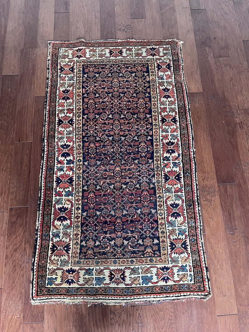 an antique malayer rug with an intricate trellis pattern and coral floral details
