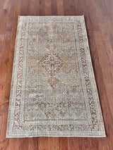 an antique persian kosakan rug with a grey/green field and oxblood accents
