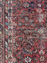 an antique malayer rug with a coral field and a blue floral trellis pattern