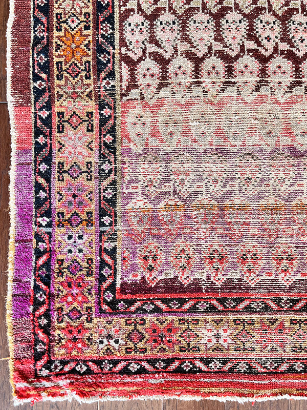 a vintage malayer rug with a pink, red and purple palette and a paisley pattern