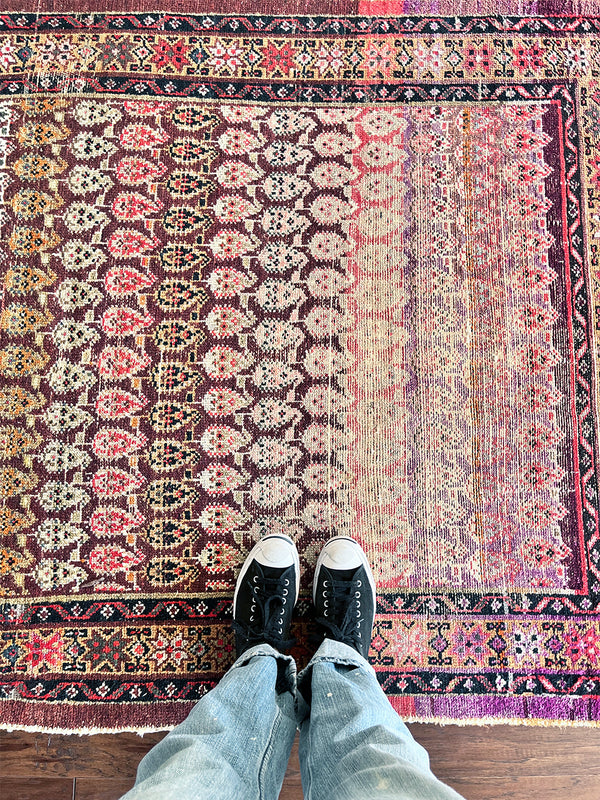 a vintage malayer rug with a pink, red and purple palette and a paisley pattern