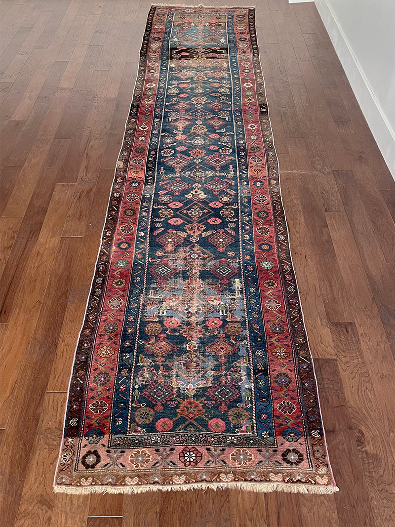 an antique malayer runner with a prussian blue field and a red floral border