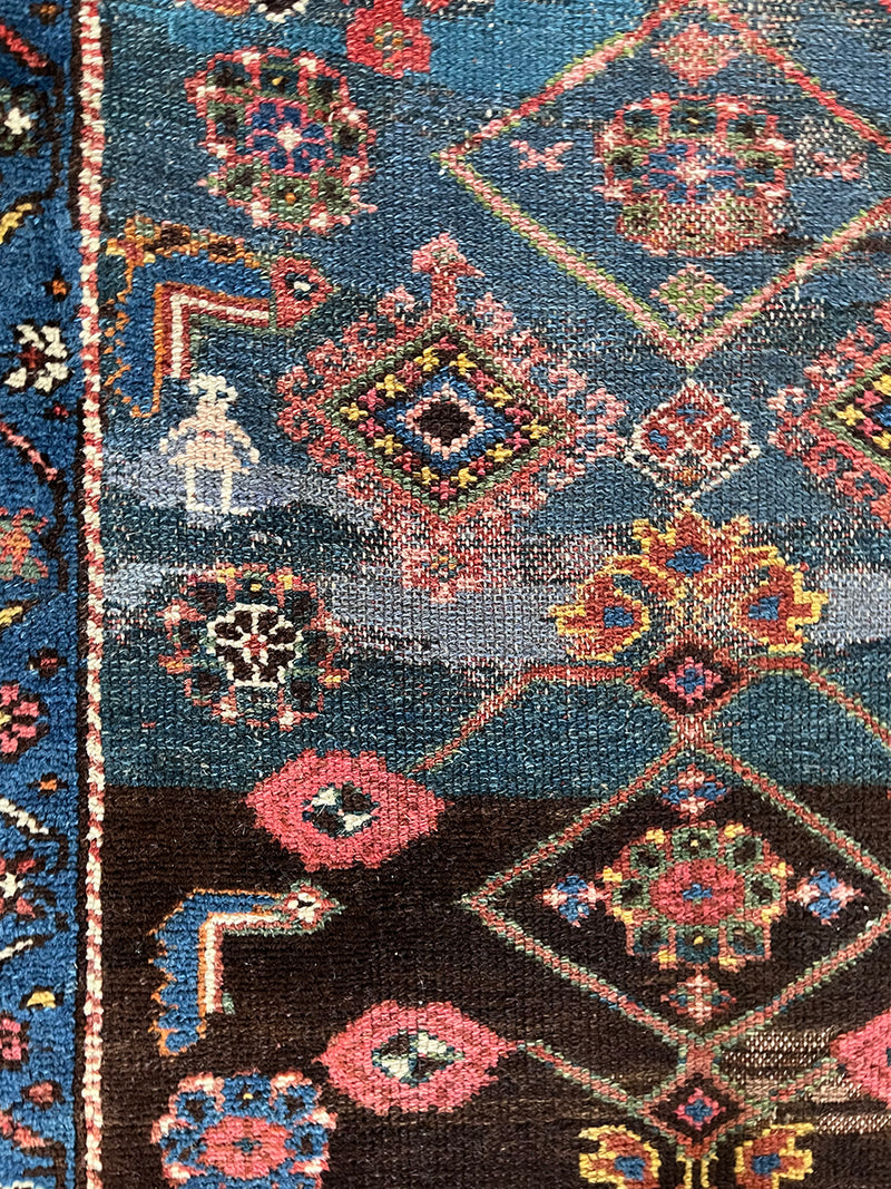 an antique malayer runner with a prussian blue field and a red floral border