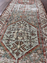 an antique kurdish runner with a grey green field, dark red and icy blue accents and a cream floral pattern