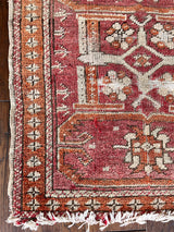 a mini antique turkish rug with a coral field and orange accents