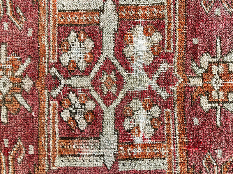 a mini antique turkish rug with a coral field and orange accents