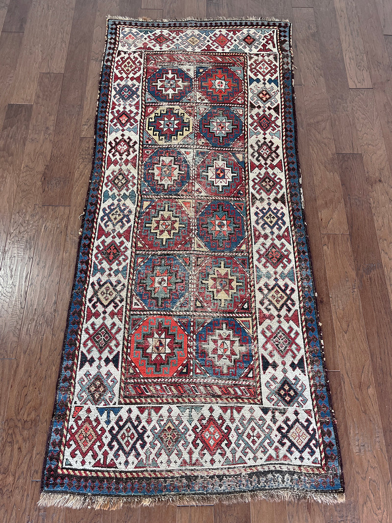 an antique kazak runner with geometric pattern in red, blue and green