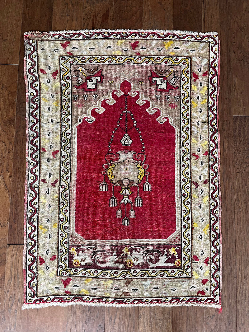 an antique turkish transylvanian rug with a pink/red field and a chandelier medallion