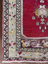 an antique turkish transylvanian rug with a pink/red field and a chandelier medallion