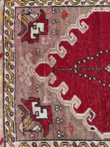 an antique turkish transylvanian rug with a pink/red field and a chandelier medallion