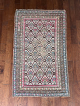 an antique caucasian rug with an ivory field and a pink and brown trellis pattern