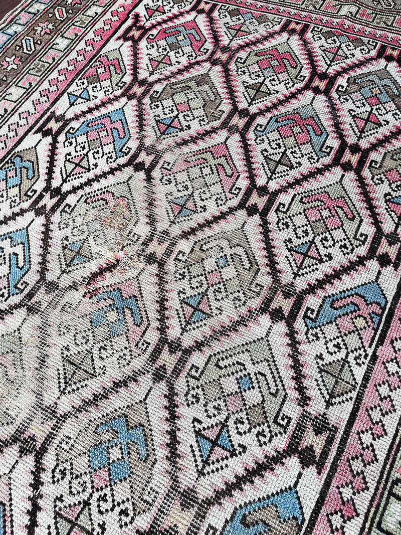 an antique caucasian rug with an ivory field and a pink and brown trellis pattern