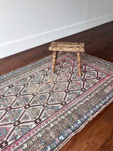 an antique caucasian rug with an ivory field and a pink and brown trellis pattern