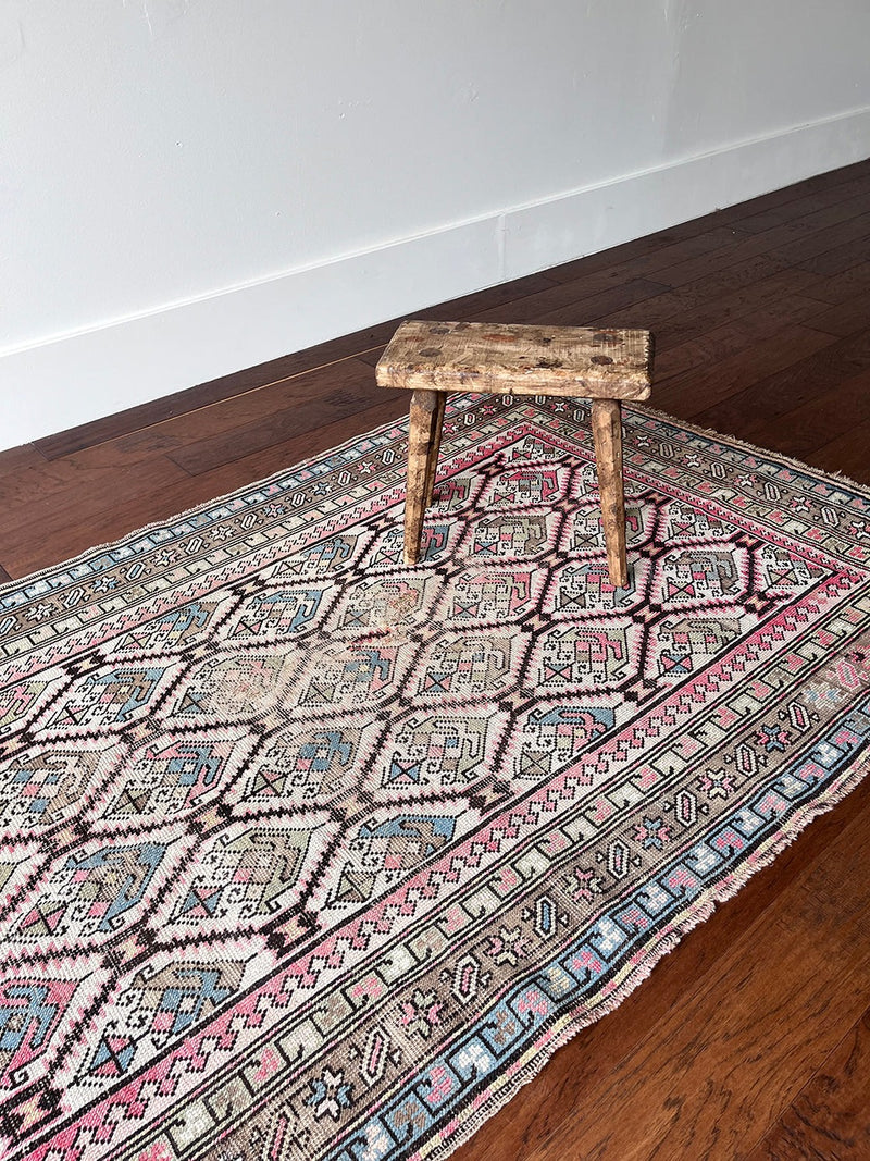an antique caucasian rug with an ivory field and a pink and brown trellis pattern