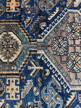 an antique shiraz rug in blue and teal tones with taupe medallions