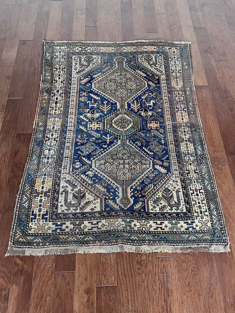 an antique shiraz rug in blue and teal tones with taupe medallions