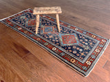 an antique mini heriz runner with a dark blue field, green accents and brick red medallions
